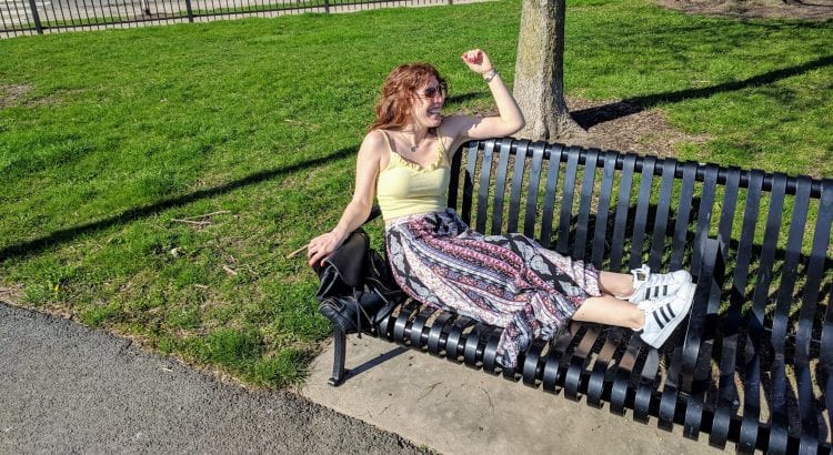 Writer Jackie Mantey sits on a bench outside in the park