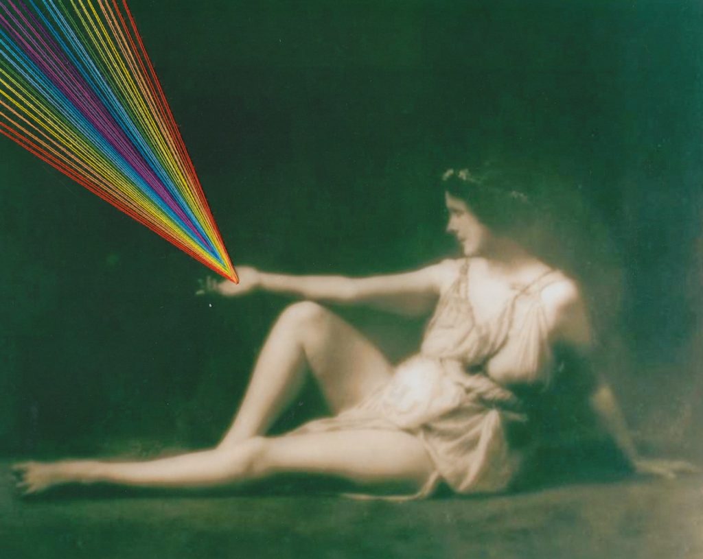 A black and white photograph of Isadora Duncan, sitting on the ground. From her right arm extended over her bent right knee, a rainbow of embroidery floss shoots from her palm.